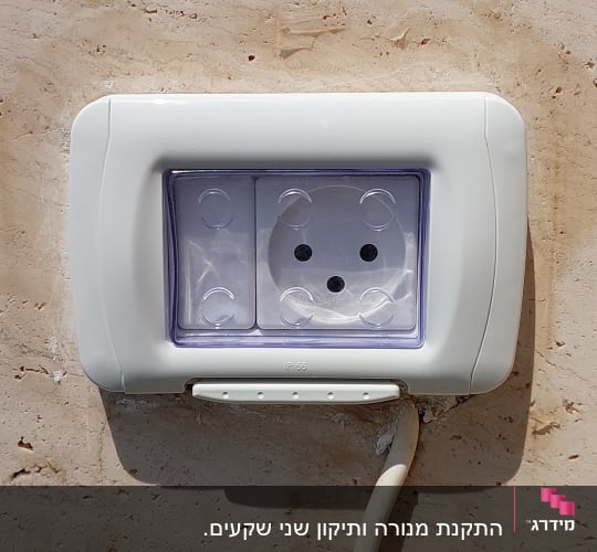 שקע חשמלי על קיר אבן עם כיסוי פלסטיק שקוף